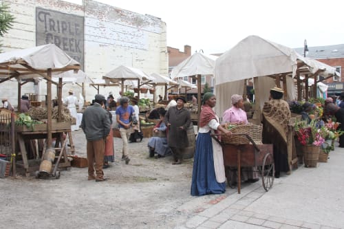 A director walks through an outdoor market scene before filming begins in Downtown St. Catharines.