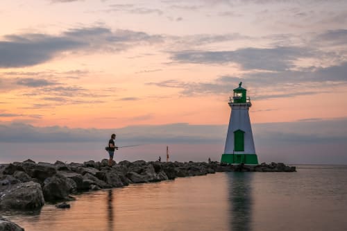 A man fishing near the lighthouse on the Port Dalhousie Pier